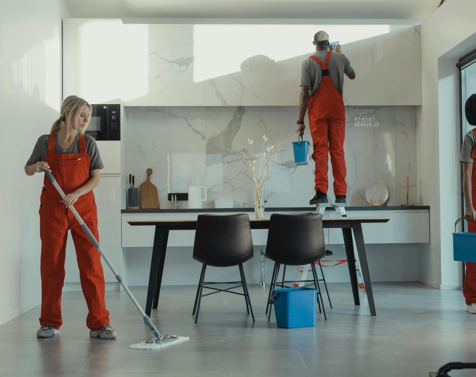 Eine Gruppe von Reinigungskräften in roten Uniformen wischt und poliert Glasflächen in einem modernen Speisesaal.
